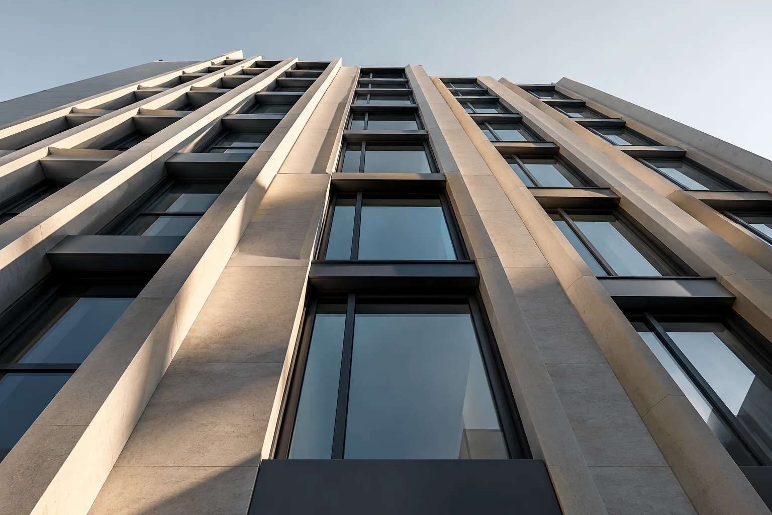 Looking steeply up the ribbed concrete and glass facade of a mid-rise building