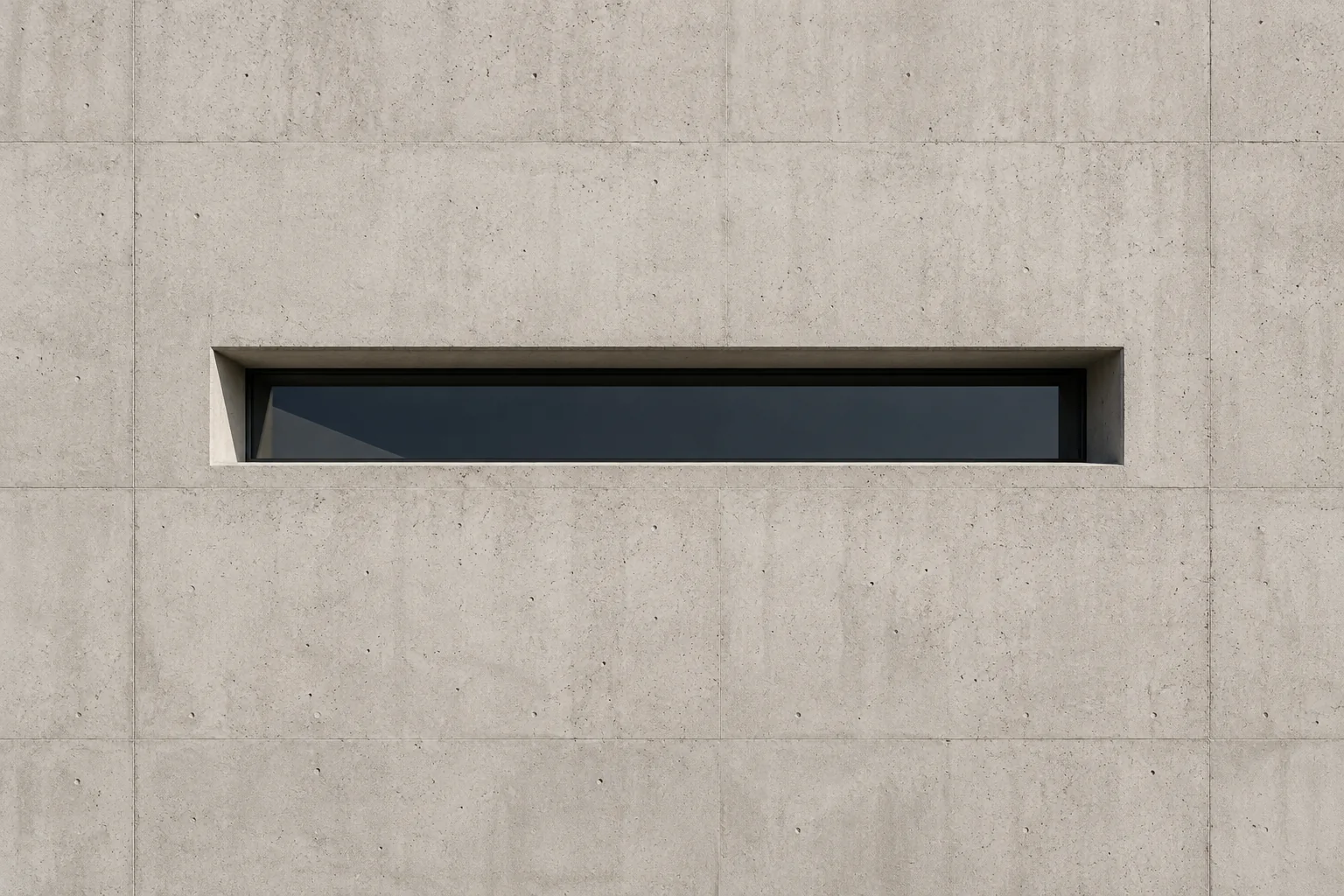 A narrow horizontal slot window set into a large smooth concrete wall