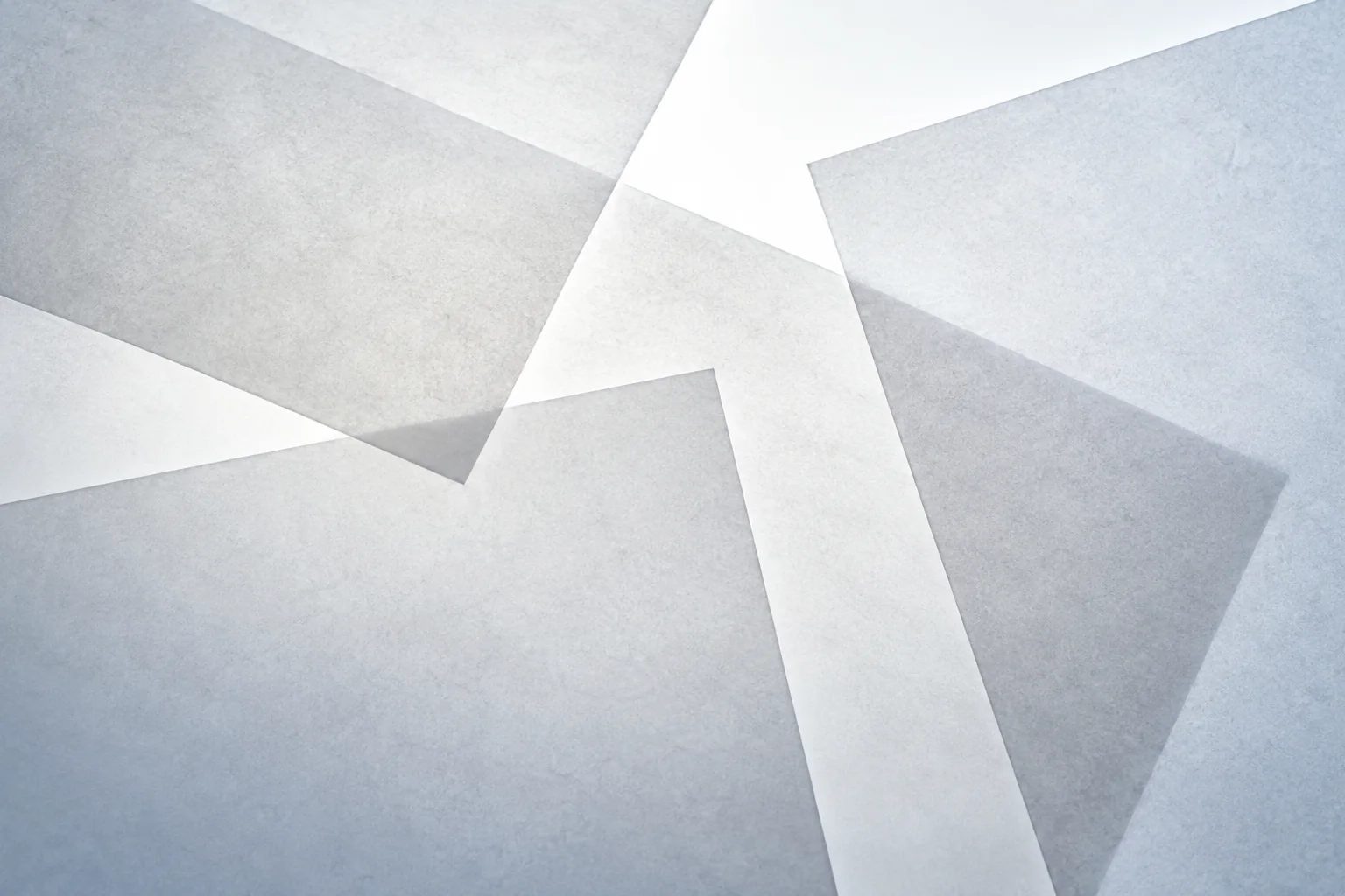 Overlapping pale geometric planes layered at angles, lit from one side