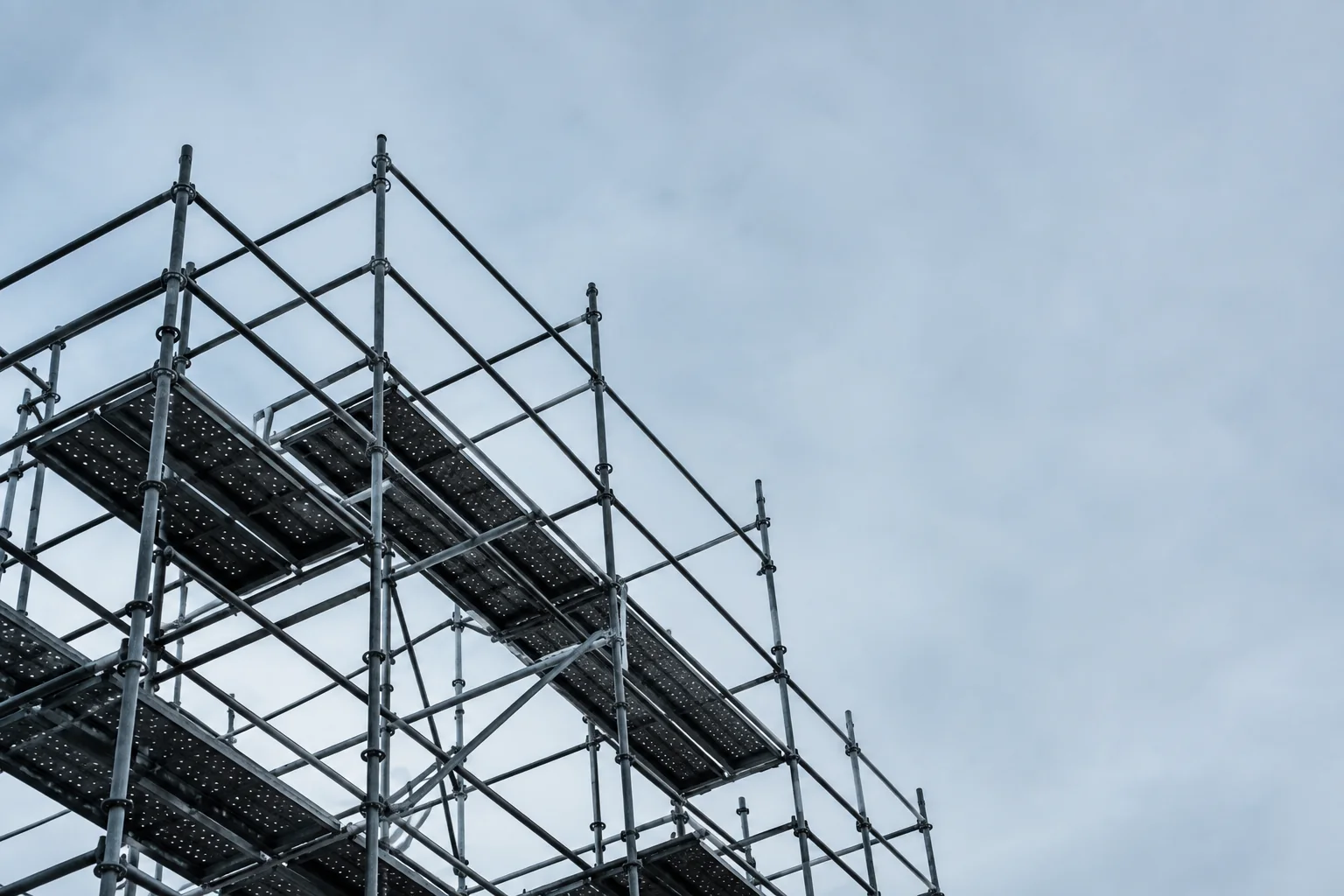 Scaffolding rising against an overcast sky, seen from below